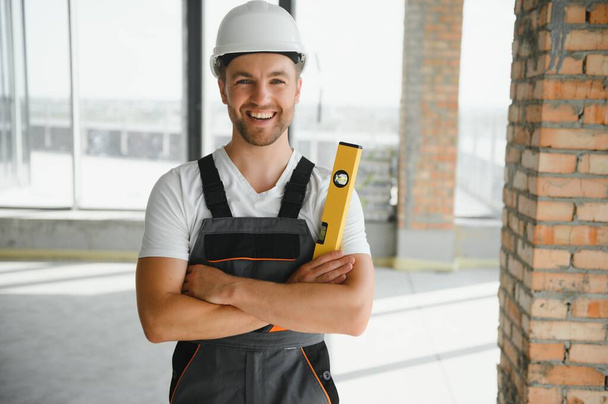 Man builder working in construction site. Male repairer in overall and helmet - Fotó, kép