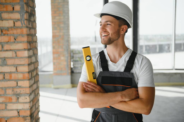 Portrait of handsome male builder in overalls and hard hat. - Foto, imagen