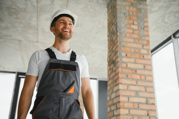 Portrait of handsome male builder in overalls and hard hat. - Foto, Imagen