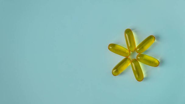 Vitamin E capsules in the form of the sun.  Vitamin D, Fish oil, Omega, Omega-3 on a blue background. Health promotion, healthy lifestyle, medicine, cosmetology, diet, mental health - Foto, Imagen