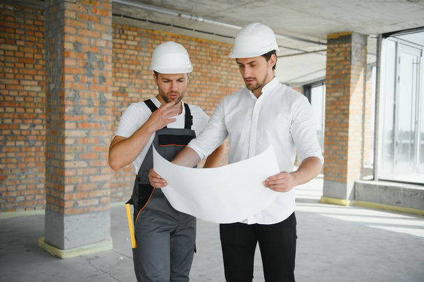 Male Architect Giving Instructions To His Foreman At Construction Site - Foto, afbeelding