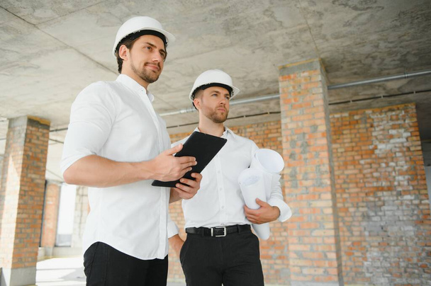 Two Specialists Inspect Commercial, Industrial Building Construction Site. Real Estate Project with Civil Engineer. - 写真・画像