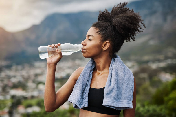 Вода очищает тело и душу. Спортивная молодая женщина пьет воду во время тренировок на открытом воздухе - Фото, изображение