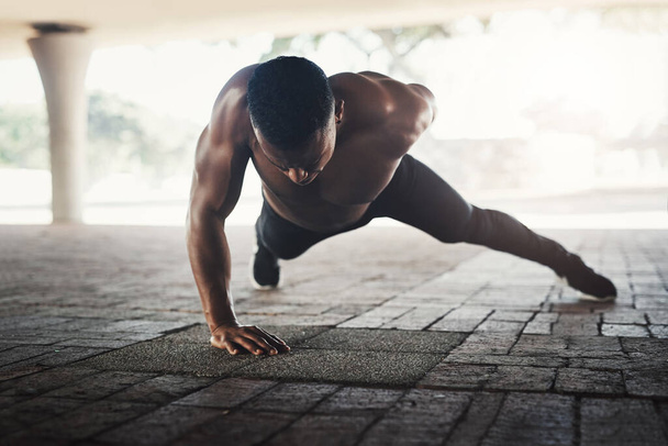 Its a show strength. Full length shot of a handsome young man doing pushups while exercising outside - Fotoğraf, Görsel