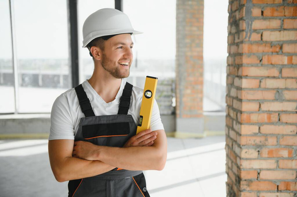 Portrait of handsome male builder in overalls and hard hat. - Photo, Image