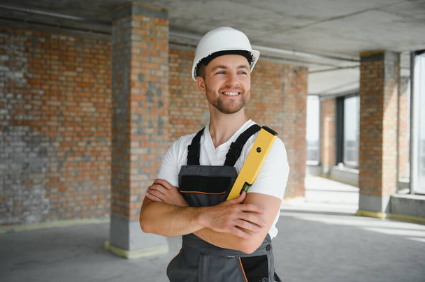 Portrait of handsome male builder in overalls and hard hat. - Fotó, kép