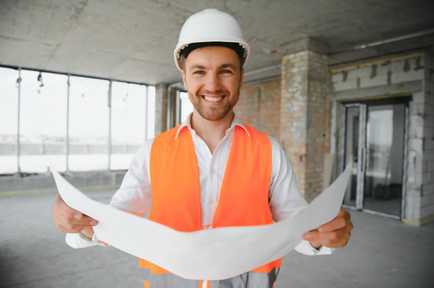 Portrait of man architect at building site. Confident construction manager wearing hardhat. Successful mature civil engineer at construction site with copy space - Photo, image