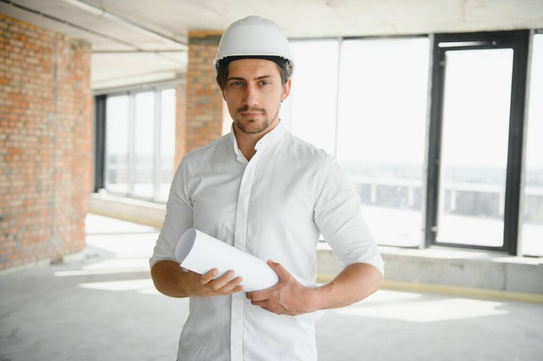 Portrait of man architect at building site. Confident construction manager wearing hardhat. Successful mature civil engineer at construction site with copy space - Zdjęcie, obraz