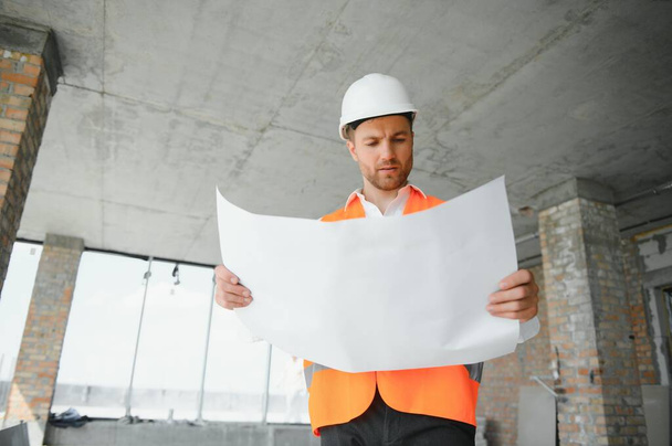 Close up engineers working on a building site holding a blueprints.Engineering and architecture concept. - Photo, image