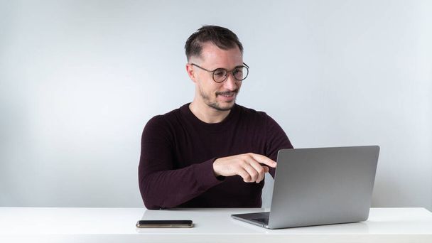 Een man communiceert via videogesprekken in een laptop aan zijn bureau. Hoge kwaliteit foto - Foto, afbeelding