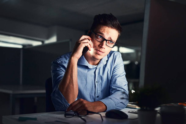 Stressed, overworked and worried while talking on phone to solve problem while working late night at the office. Serious and exhausted man calling IT about computer issue trying to reach deadline. - 写真・画像