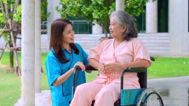 Asian careful caregiver or nurse taking care of the elderly Asian patient in a wheelchair. Concept of happy retirement with care from a caregiver and Savings and senior health insurance. elderly care - Footage, Video