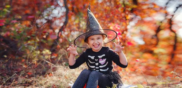 Young girl in black costume goes trick or treating. Little witch, Kids with jack-o-lantern. Children with candy bucket in fall forest. Happy Halloween. - Фото, зображення