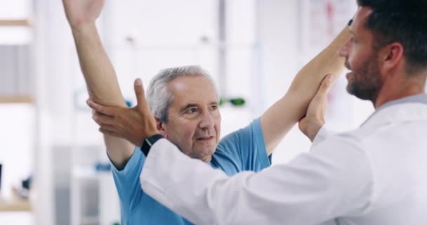 A physiotherapist consulting and showing support with mature patient. Happy health care worker motivating a senior male, practicing movement and exercise as recovery treatment after having a stroke. - Filmagem, Vídeo