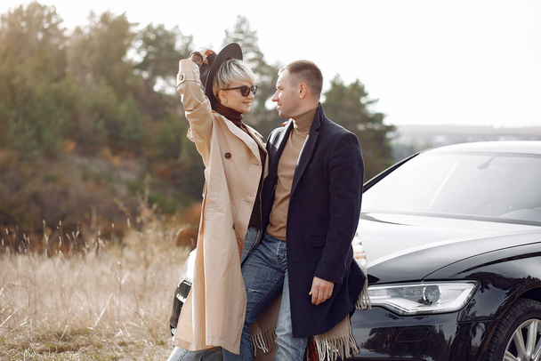 Couple in a field. Girl in a brown coat. Man with his wife near the car - Photo, image
