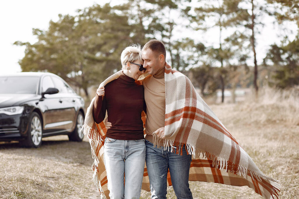 Couple in a field. Girl in a brown coat. Man with his wife near the car - Foto, Imagen