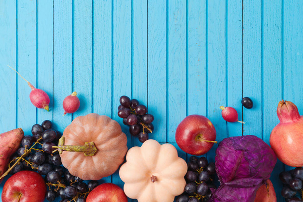 Autumn harvest background in trendy color.  Pumpkin, apple, grapes and vegetables on blue wooden background. Top view, flat lay - 写真・画像
