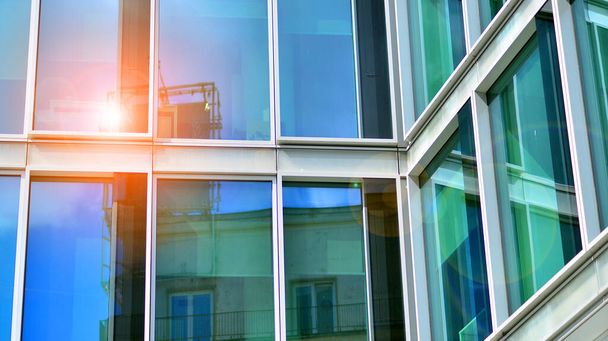 Moderne Glasfassade vor blauem Himmel. Untere Ansicht eines Gebäudes im Geschäftsviertel. Niedriger Blickwinkel auf die Glasfassade eines Bürogebäudes. - Foto, Bild