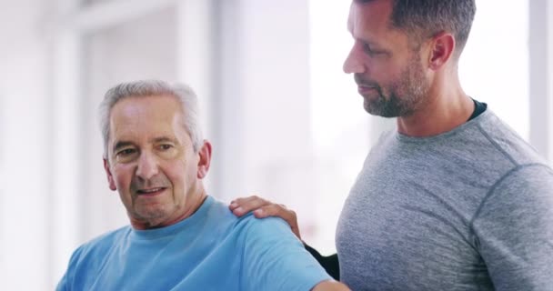 Senior man doing physical therapy with a trainer, lifting a dumbbell in physiotherapy and recovering from an injury with a physiotherapist. Retired patient training with a coach at a sports center. - Filmagem, Vídeo