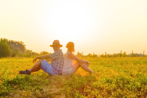 Portrait, in backlit, of a couple sitting in a meadow. - Photo, image