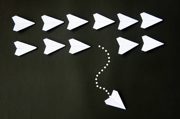 White paper plane origami leaving other white planes on dark background. Leadership skills concept. - Foto, Imagem