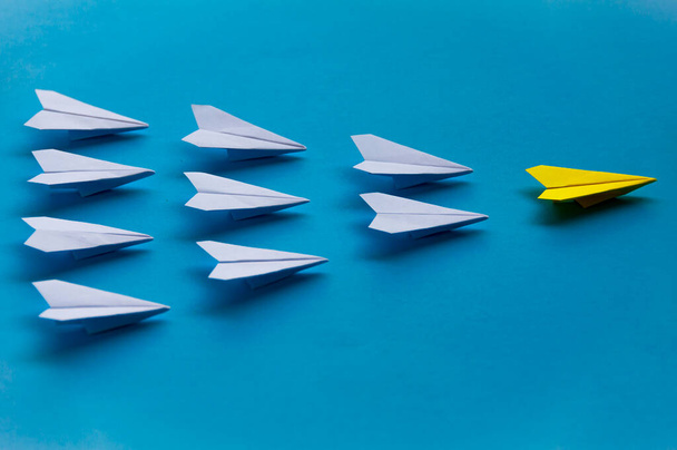 Yellow paper plane origami leading white planes on blue background. Leadership skills concept. - Foto, immagini
