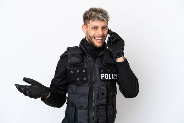 SWAT caucasian man isolated on white background keeping a conversation with the mobile phone with someone - Фото, изображение