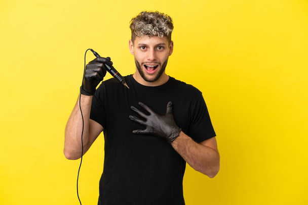 Tattoo artist caucasian man isolated on yellow background surprised and shocked while looking right - 写真・画像