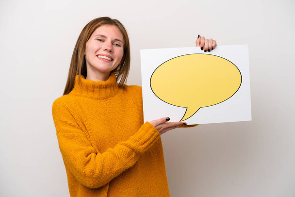Fiatal angol nő elszigetelt fehér háttér kezében egy plakát beszéd buborék ikon és rámutatva, hogy - Fotó, kép