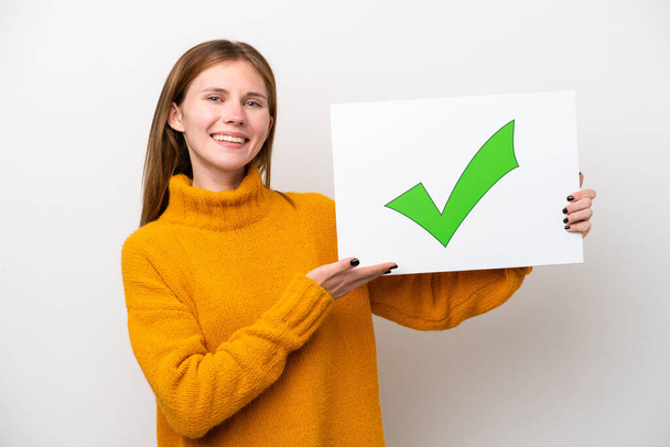 Young English woman isolated on white background holding a placard with text Green check mark icon and  pointing it - Photo, Image