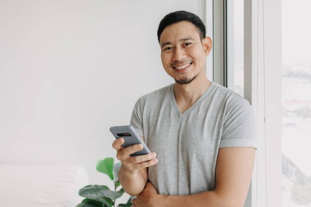 Young happy smiling asian man using smartphone feel relax and comfortable. - Foto, Imagem