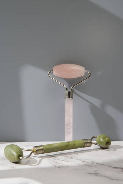 Rose quartz and jade facial roller for anti aging facial massage. Skin care luxury beauty tools. - 写真・画像