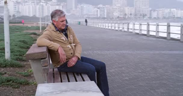 Unhappy mature man suffering from mental health issues, looking sad and depressed while sitting outdoors. Senior male trying to process bad news or test results, after finding out he has cancer. - Záběry, video