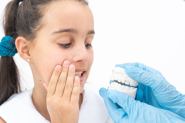 Hammaslääkäri on tarkistaa ja asettaa mitan suluissa. Puhuu tyttö noin hammasraudat suussaan
. - Valokuva, kuva