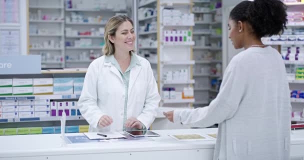 Professional female healthcare pharmacist helping customer at the counter in a pharmacy. Woman health consultant or doctor aiding patient with prescription medication in a medical clinic store - Video