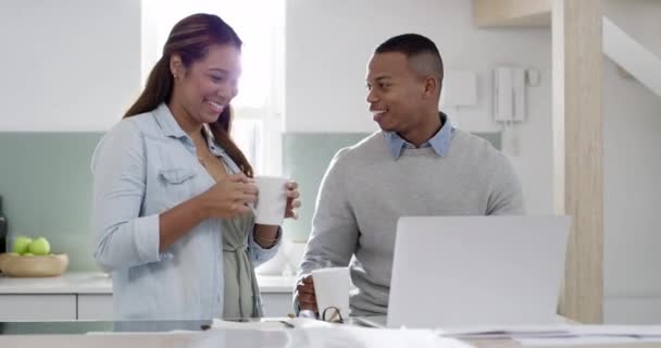 Couple paying bills on laptop and talking while looking at debt, loan or tax payment details online. Woman drinking coffee and distracting her freelancing husband while working from home kitchen. - Materiaali, video