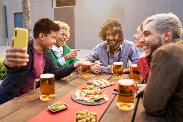 friends taking selfie and drinking beer at bar. High quality photo - Photo, Image
