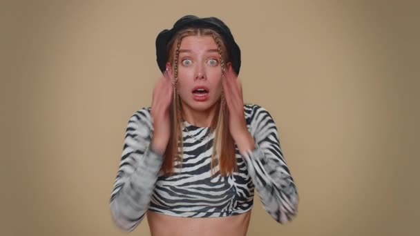 Scared fearful young woman covering ears with hands, closing eyes, meeting own phobia, evidence horror event, screaming, shouting at loud, freaked out. Adult stylish girl on beige studio background - Záběry, video