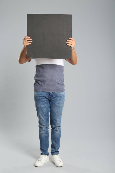 Man holding black blank poster on grey background. Mockup for design - Photo, Image