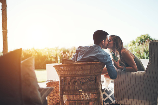 Только для твоих губ. Снимок ласковой молодой пары, целующейся, наслаждаясь пивом во внутреннем дворике - Фото, изображение