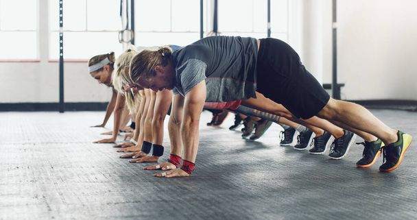 Gym - the body transformation station. a group of young people doing push ups in a gym - Foto, Imagem