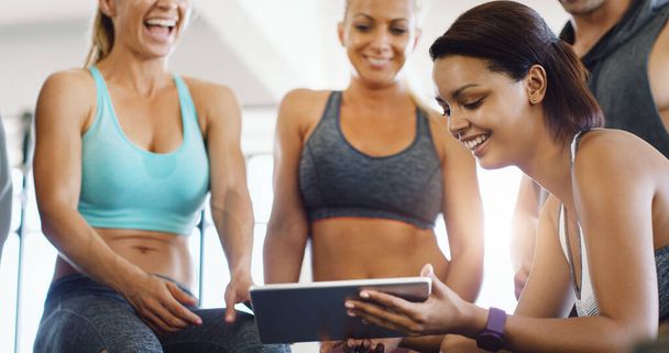 Ничто не сравнится с небольшой мотивацией мышц благодаря интернету. группа счастливых молодых женщин с цифровым планшетом в тренажерном зале - Фото, изображение