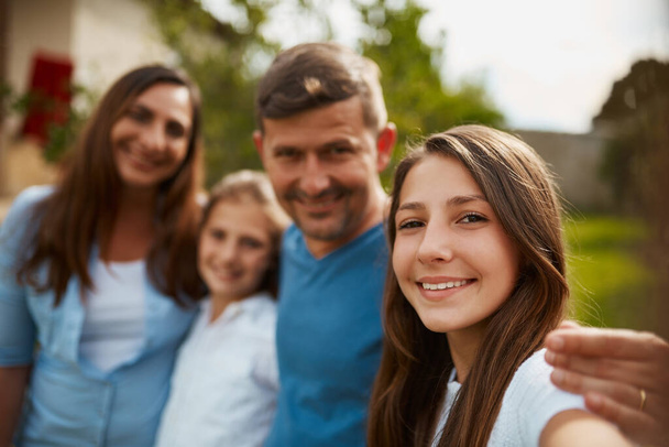 Сім'я означає для мене світ. Обрізаний портрет молодої сім'ї з чотирьох стоячих зовні
 - Фото, зображення