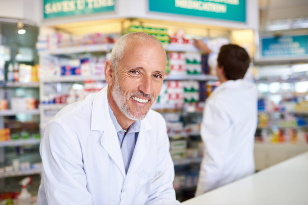 Come see me for any healthcare advice you need. Portrait of a mature pharmacist working in a chemist - Foto, imagen