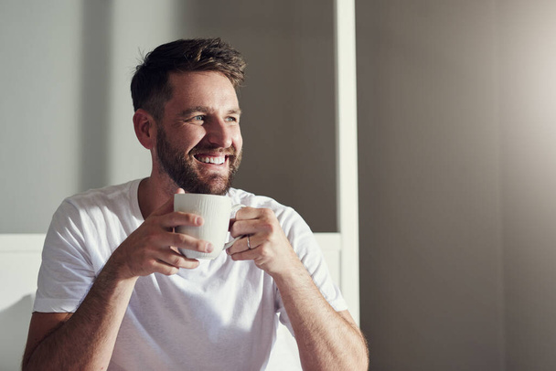 Theres so much to love about a fresh cuppa coffee. a handsome young man drinking coffee in the bedroom at home - Foto, Imagem