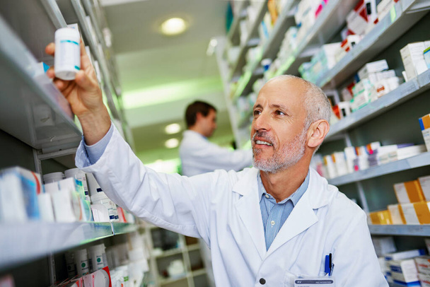 Aha I knew we had it in stock. a mature pharmacist doing inventory in a pharmacy - Foto, Bild