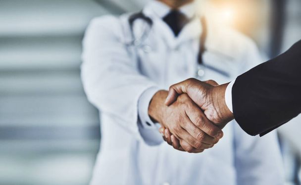 Adding the corporate factor to healthcare. a doctor shaking hands with a businessman in a hospital - 写真・画像