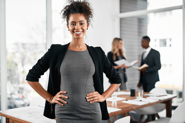 My confidence has grown with my success. Portrait of a young businesswoman standing in an office with her colleagues in the background - Foto, Imagen
