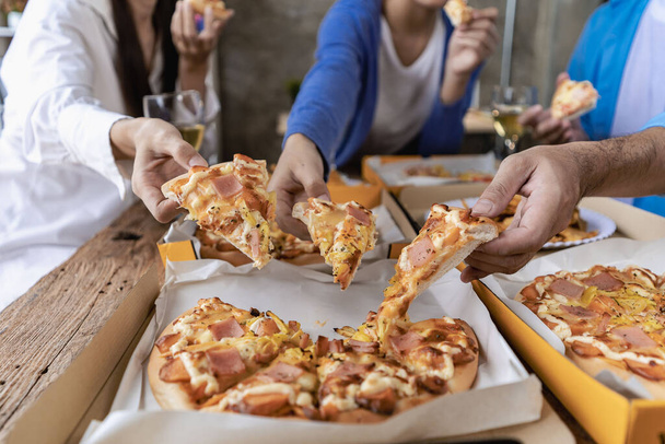 Group of male and female colleagues having pizza lunch together at the office after work celebration concept - Photo, Image