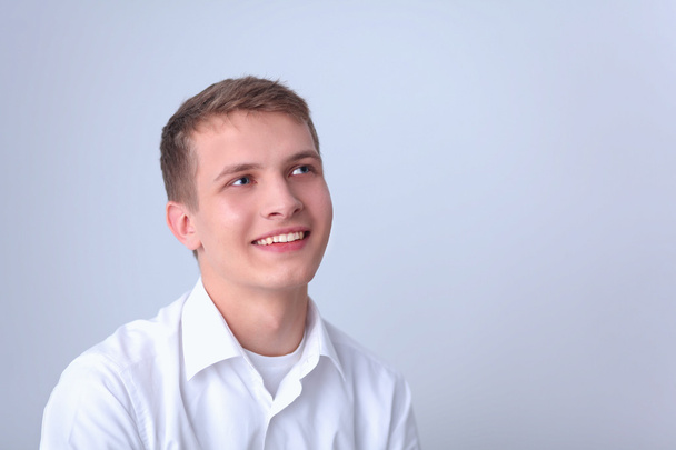 Portrait of young man smiling isolated on gray background - Foto, afbeelding